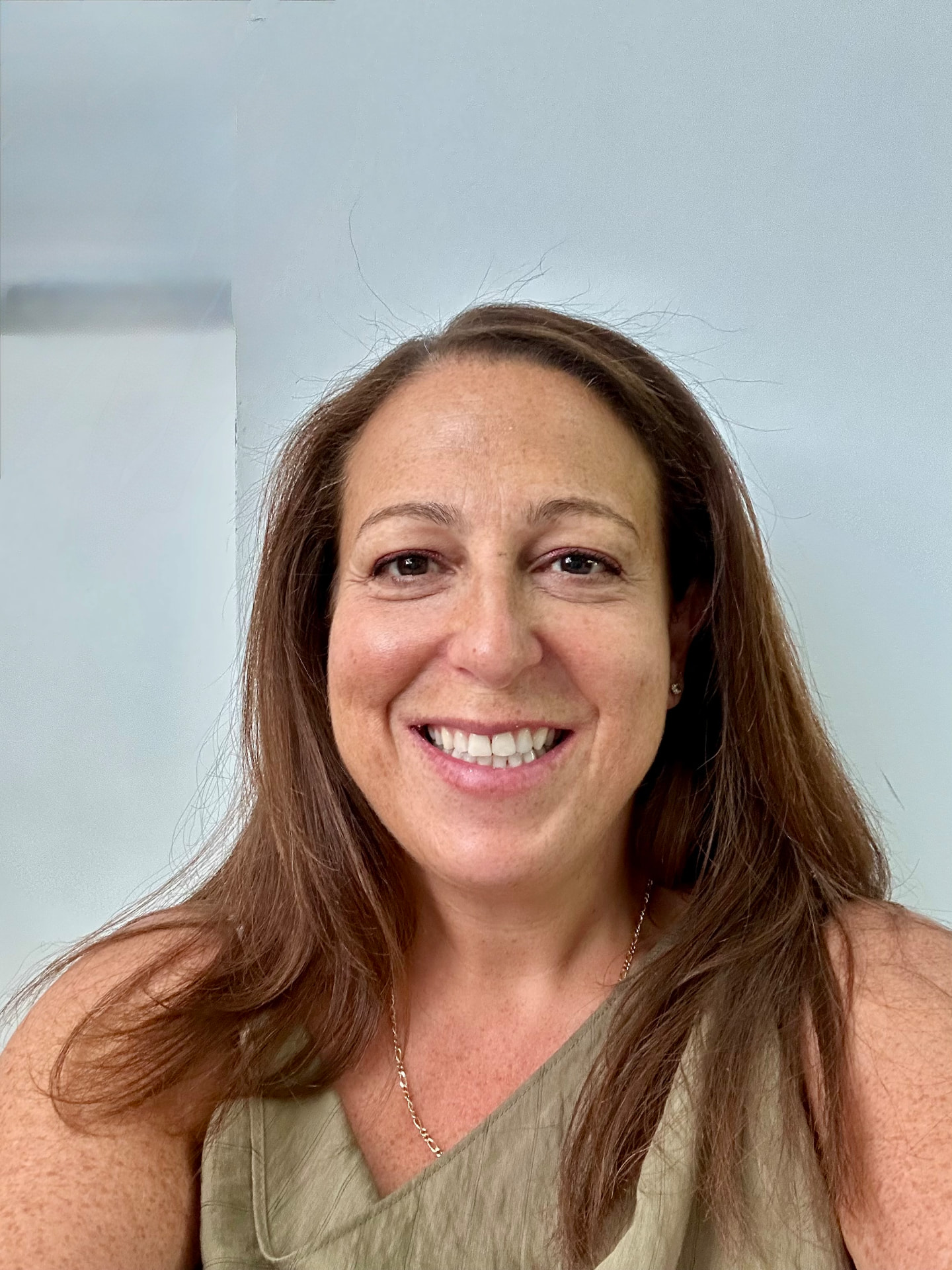 Hannah Cohen, Inclusion Coach, smiling in a green top against a light background